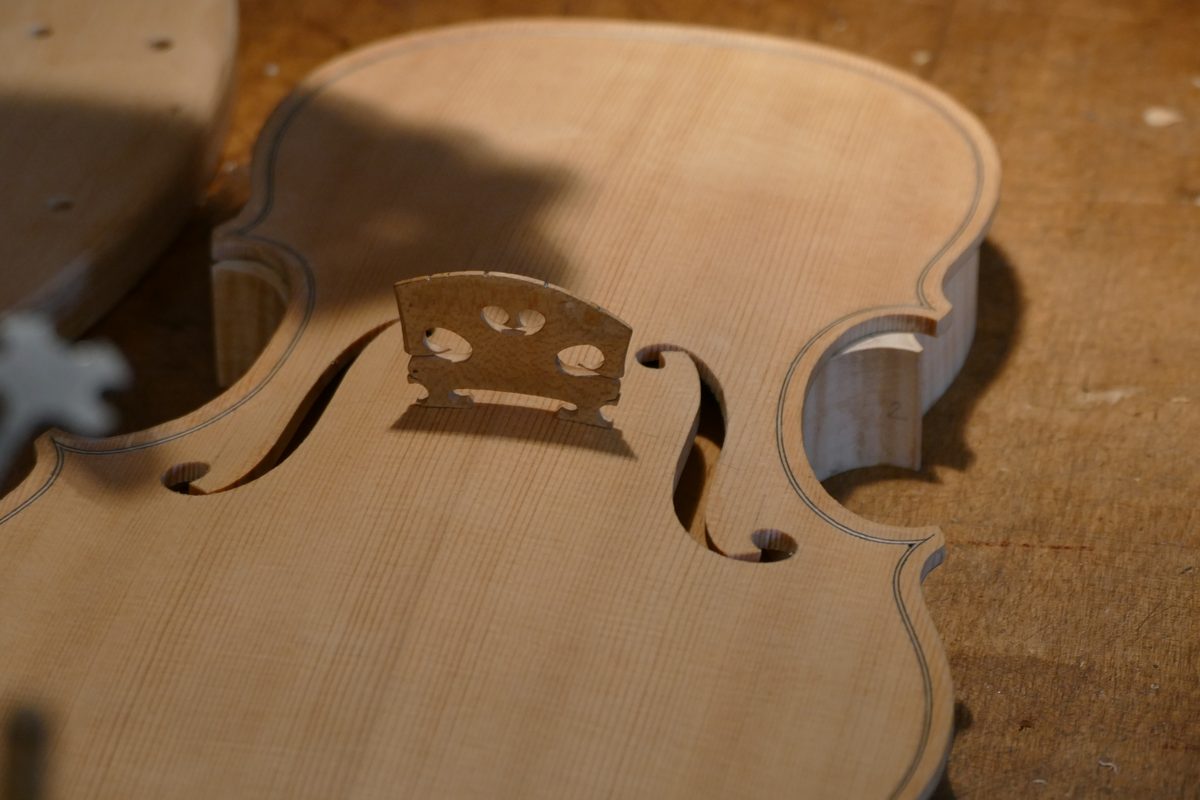 An unfinished violin on a luthier's bench, with tools and wood shavings around it