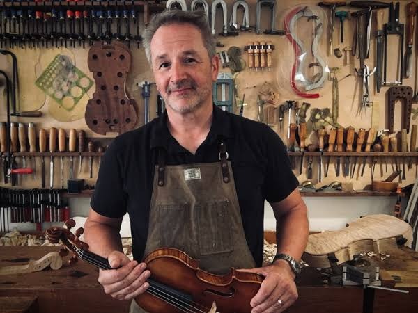 Kelvin Scott holding a violin in his workshop